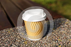 Paper cup on parapet outdoors, closeup. Coffee to go