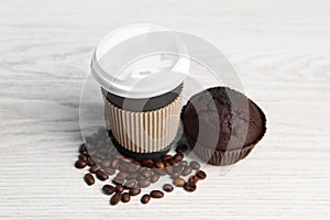 Paper cup with plastic lid, muffin and coffee beans on white wooden table. Coffee to go