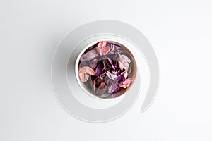 Paper cup of purple and pink dry flowers, branches, leaves and petals on white background