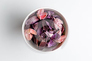Paper cup of purple and pink dry flowers, branches, leaves and petals on white background
