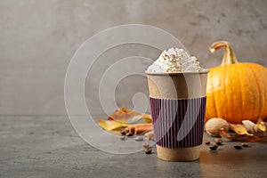 Paper cup with tasty pumpkin spice latte on grey table