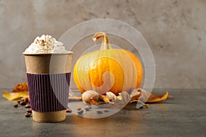 Paper cup with tasty pumpkin spice latte on table. Space for text