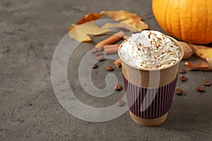 Paper cup with tasty pumpkin spice latte on table. Space for text