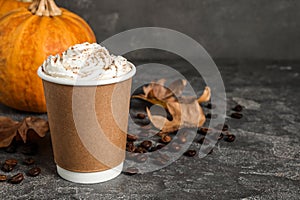 Paper cup with tasty pumpkin spice latte on table. Space for text