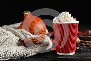 Paper cup with tasty pumpkin spice latte on wooden table