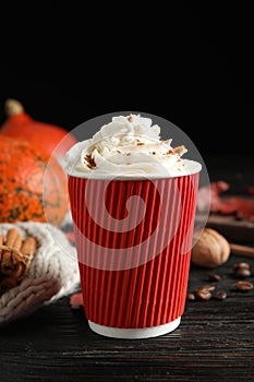 Paper cup with tasty pumpkin spice latte on wooden table