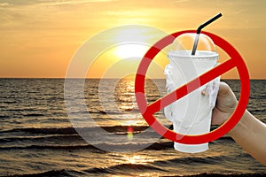 Paper cup white and straws in hand over sea beach sunset evening and stop red sign forbidden symbol, campaign no use and ban