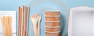 Paper cups, dishes, bag, wooden forks, drinking straws, fast food containers, wooden cutlery on light blue background. Eco craft p