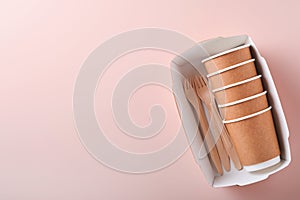 Paper cups, dishes, bag, wooden forks, drinking straws, fast food containers, wooden cutlery on pink background. Eco craft paper