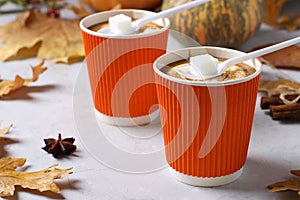 Paper cups with tasty pumpkin latte and spice on gray table. Closeup