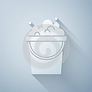 Paper cut Bucket with soap suds icon isolated on grey background. Bowl with water. Washing clothes, cleaning equipment