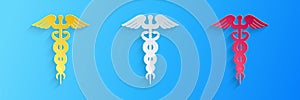 Paper cut Caduceus medical symbol icon isolated on blue background. Medicine and health care concept. Emblem for drugstore or