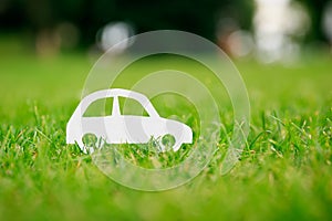 Paper cut of car on green grass