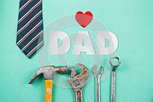 Paper cut of DAD text with old rusty tools and tie on green paper background, Happy Father`s Day