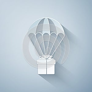 Paper cut Gift box flying on parachute icon isolated on grey background. Delivery service, air shipping concept, bonus