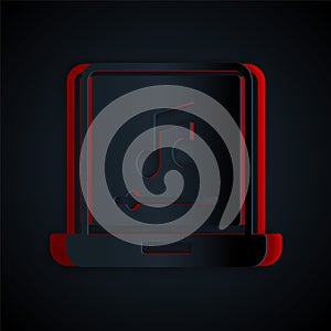 Paper cut Laptop with music note symbol on screen icon isolated on black background. Paper art style. Vector