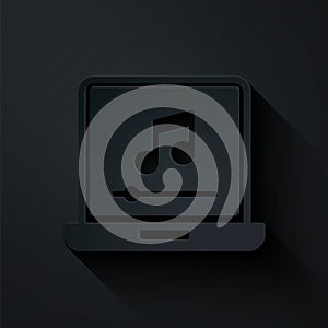 Paper cut Laptop with music note symbol on screen icon isolated on black background. Paper art style. Vector