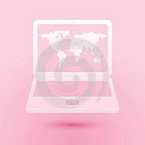 Paper cut Laptop with world map on screen icon isolated on pink background. World map geography symbol. Paper art style