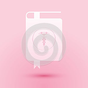 Paper cut Medical book and Caduceus medical icon isolated on pink background. Medical reference book, textbook