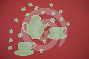 Paper cut out of teapot and cups on red background