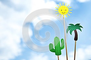 Paper cut palm tree, cactus and winking smiling sun on sticks