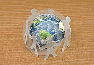 Paper cut of people standing in a circle around globe