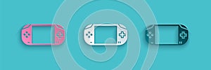 Paper cut Portable video game console icon isolated on blue background. Gamepad sign. Gaming concept. Paper art style