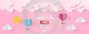 Paper cut of Valentine`s Day sale background with pink and blue heart hot air balloons, sun and cloud on pink background, banner