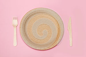 paper disposable plate with bamboo fork and knife on pink background