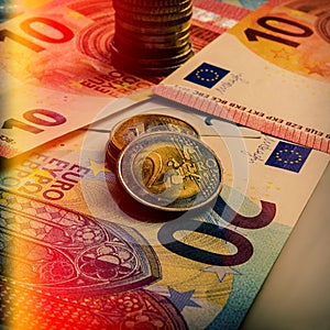 Paper euro banknotes and coins. The coin is two euros.