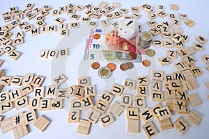 paper euro banknotes, piggy bank, bills on table among euro coins, word job with wood blocks, concept of employee salary,