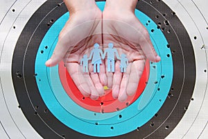 Paper family in hands on archery target background
