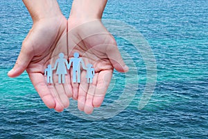 Paper family in hands on blue sea background welfare concept
