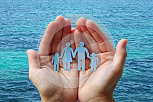 Paper family in hands on blue sea background welfare concept