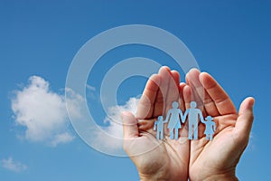 Paper family in hands on blue sky background welfare concept photo