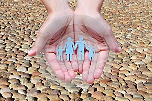 Paper family in hands on cobblestone road background