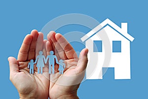 Paper family in hands with white home on blue background welfare concept