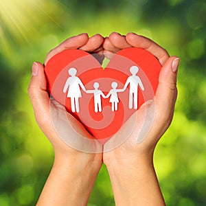 Paper Family and Heart in Hands over Green Sunny Background