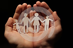 A paper family holding hands, with the protection of hands.