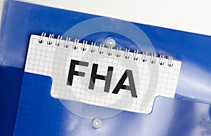 Paper with FHA loan on table with blue folder