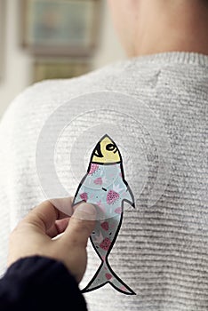 Paper fish in the back of man for april fools day