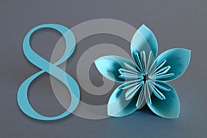 Paper flower from origami with the number eight on a gray background. March 8, International Women`s Day.