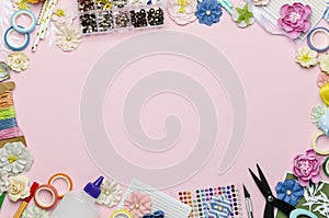 Paper flowers, scissors, paper and scrapbooking items on pink background