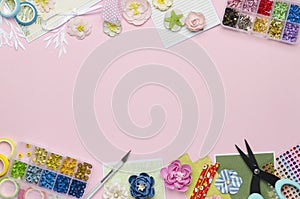 Paper flowers, tools, paper and scrapbooking items on pink background