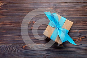 Paper gift box with blue ribbon on dark wood background. top view with copy space