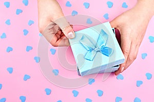 Paper gift box with a bow in the woman`s hands