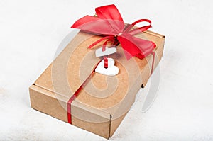 Paper gift box with red bow and white wooden hearts for Valentin