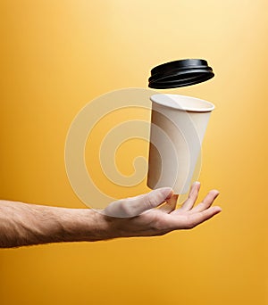 A paper glass for hot drinks levitates over a man`s palm, close-up