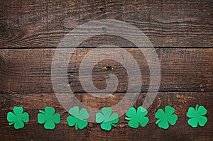 Paper green clover shamrock leaf border on dark wooden background