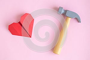Paper heart and hammer toy on rose background abstract